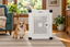A Corgi sitting beside Impact's white Stationary Dog Crate in a living room.