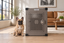 A French Bulldog sitting beside Impact's gray Stationary Dog Crate in a living room.