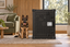 A German Shepherd sitting beside Impact's black High Anxiety Crate in a living room.