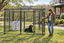 10x10 kennel with a black dog and white crate, with a woman holding the open gate #size_10x10